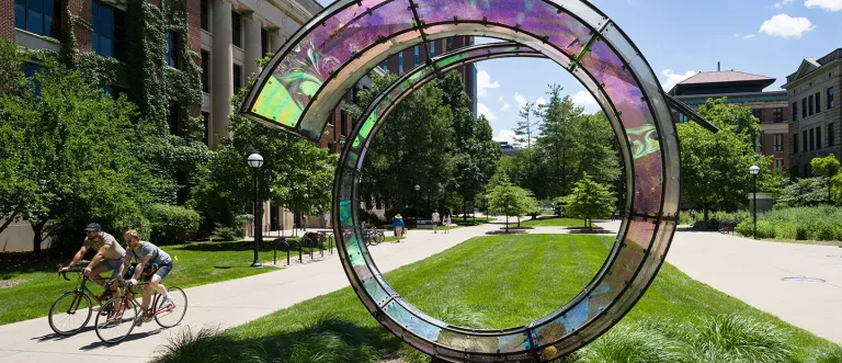 Two Bicyclists on the left of Sculpture Ring in Summer